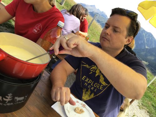 Neil practicing proper fondue etiquette by stirring the cheese while he dips