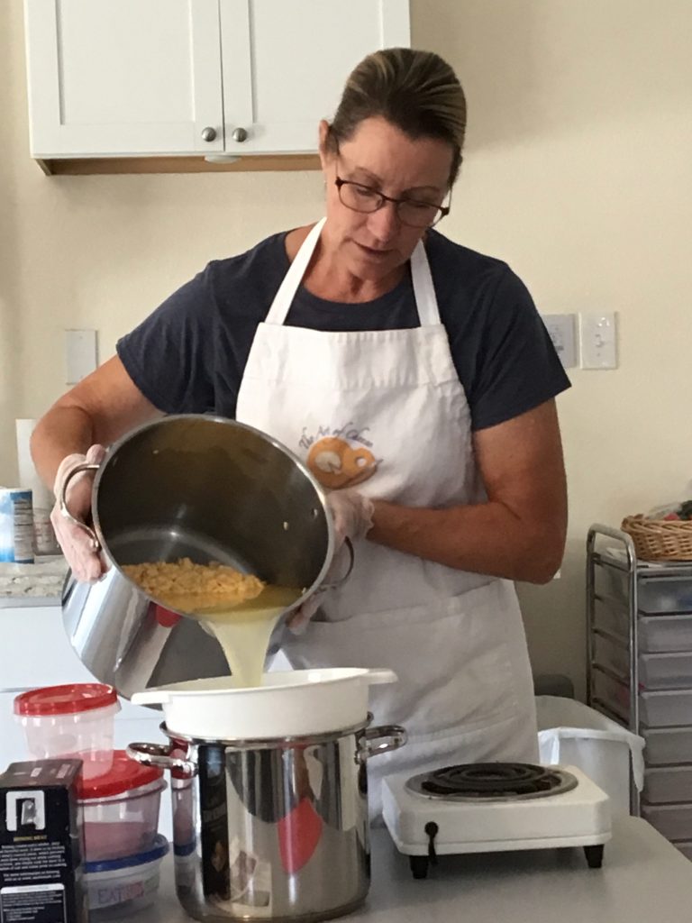 Kate draining the whey into the pot to keep the next step warm