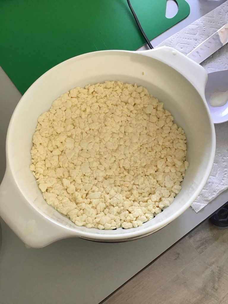 The first round of the curds being pressed into the colander